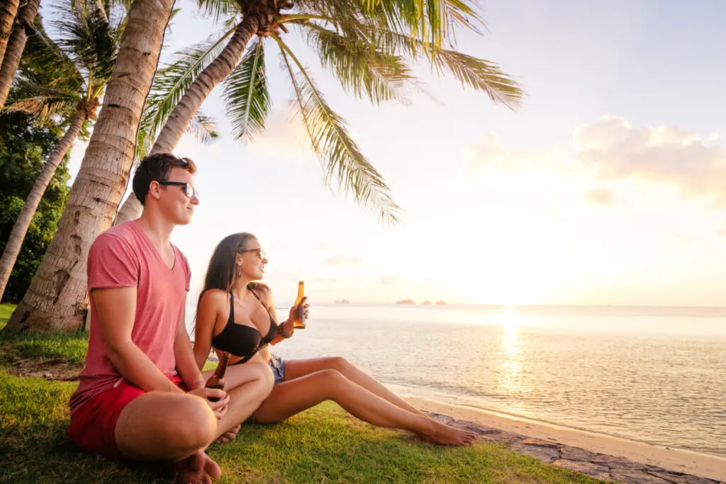 Couple on tropical island with beers in hand