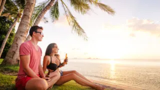 Couple on tropical island with beers in hand