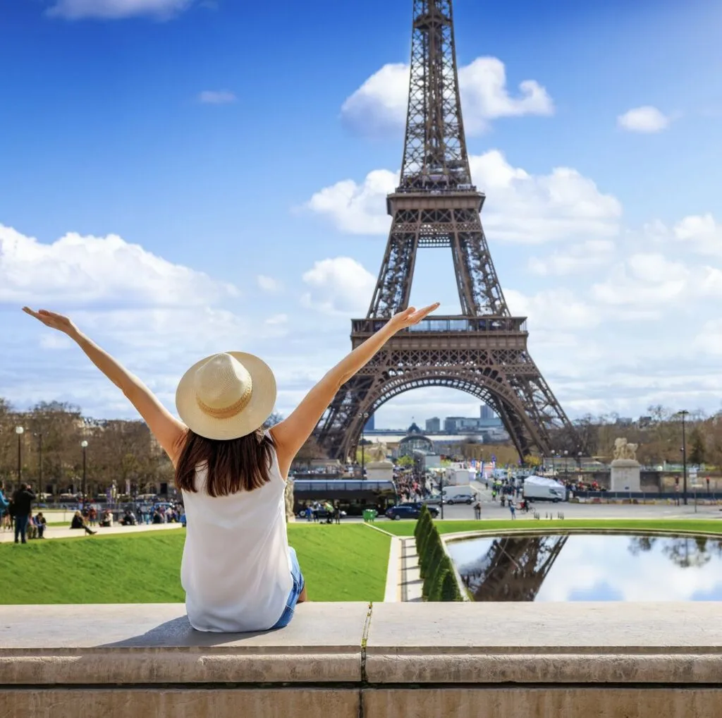 A tourist woman enjoys the beautiful view of the Eiffel Tower in Paris, France, during a sunny spring day