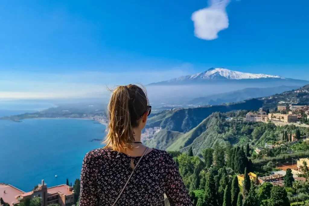A female traveler standing overlooking Mount Etna