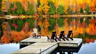 Chairs lakeside amongst vibrant fall foliage