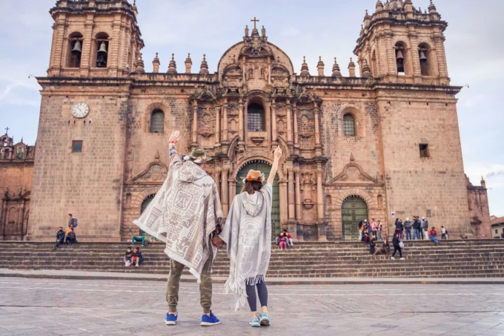 Travelers posing in front of Cusco cathedral in Peru