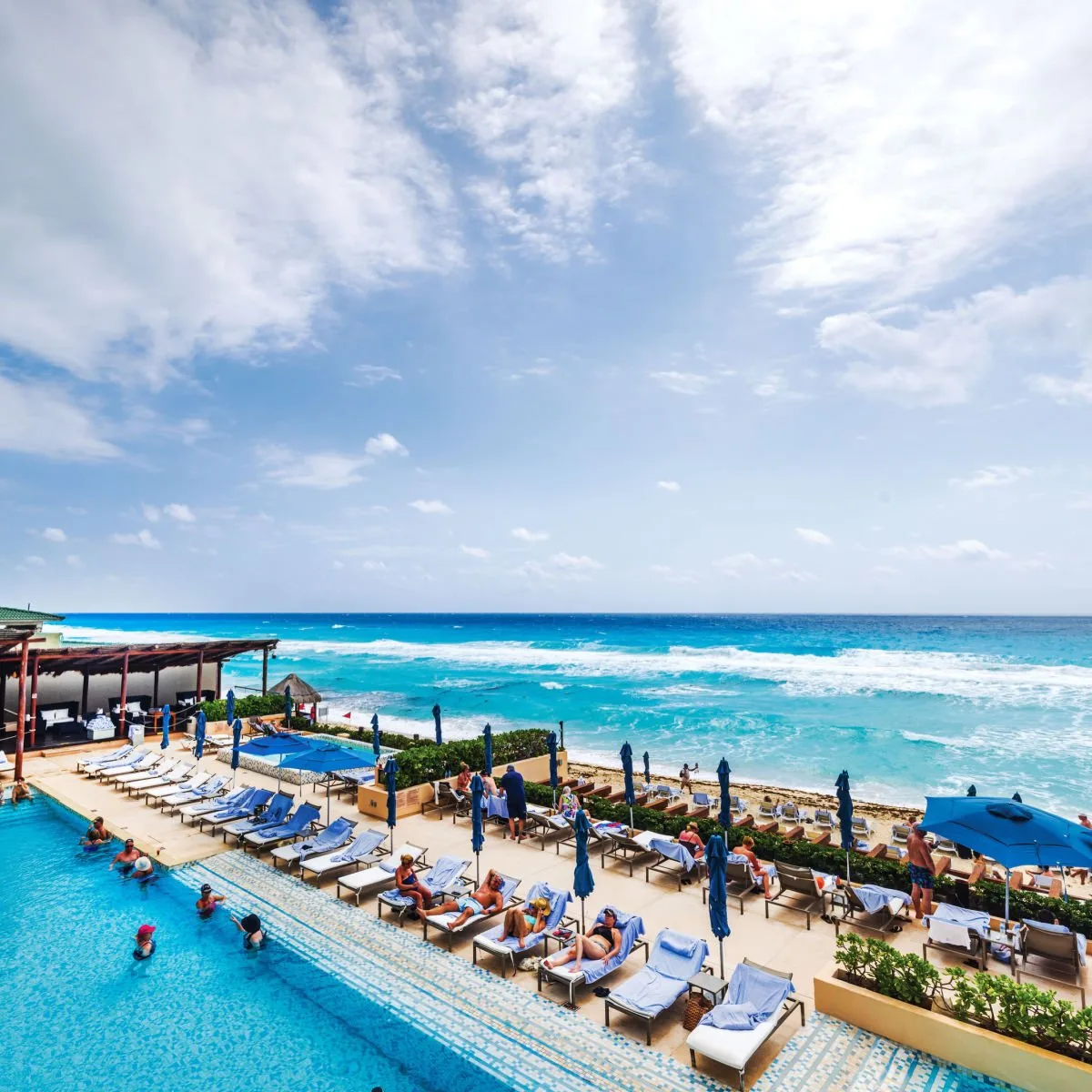 Vacationers at resort pool with ocean view in Cancun, Mexico